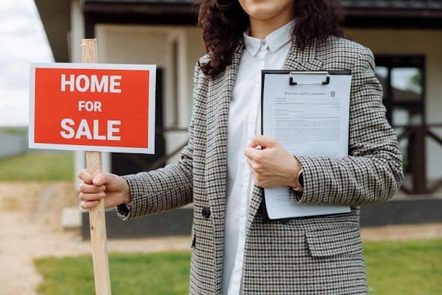 real estate agent holding up a home for sale sign