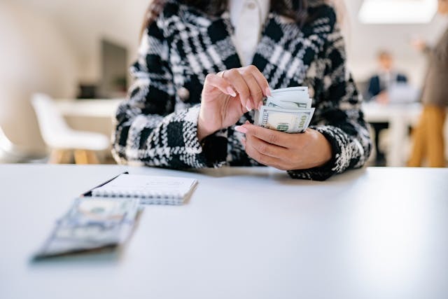 person counting money over a notebook