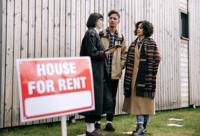 house for rent sign in front of three people