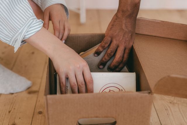 two people putting objects in boxes