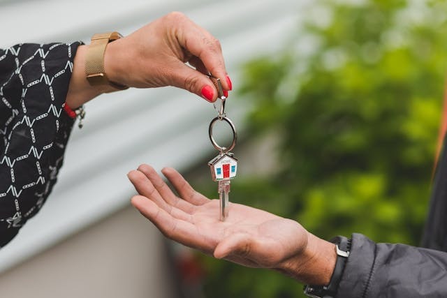 person passing a house shaped key to another