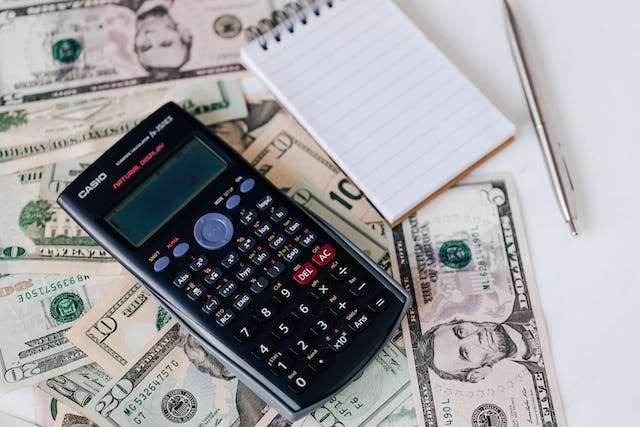 dollar-bills-spread-out-o-a-table-with-a-calculator-and-notepad-and-pen