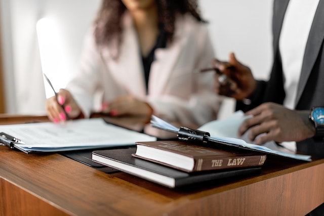 two people looking over documents with law books next to them